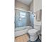 Modern bathroom with a shower and bathtub combination behind a glass door with neutral tiling at 1536 Pine Island Rd, Kissimmee, FL 34744