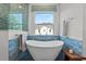 Bright bathroom with a modern free standing tub, blue tiling, a window and wood accents at 1536 Pine Island Rd, Kissimmee, FL 34744