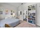 Well-lit bedroom with neutral tones, wood floors, and a bookshelf filled with books and photos at 1536 Pine Island Rd, Kissimmee, FL 34744