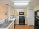 Functional kitchen featuring a stainless sink, black appliances, and wood-look flooring at 1910 Summer Club Dr # 108, Oviedo, FL 32765