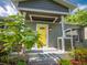 Covered front porch with a bright yellow door and lush landscaping at 2100 Forest Cir, Orlando, FL 32803