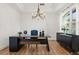 This home office features a large desk, modern chandelier, wood floors and a large window at 218 Pebblerock Ct, Orlando, FL 32828