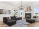 Bright living room featuring a dark gray sectional, fireplace with marble surround, and stylish chandelier at 218 Pebblerock Ct, Orlando, FL 32828