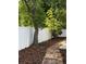 Backyard landscape design featuring a brick walkway, mulch, and white vinyl fence at 2325 E Harding Street, Orlando, FL 32806