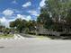 Community entrance showcasing the 'Osprey Cove' sign with palm trees and buildings in the backdrop on a sunny day at 2826 Osprey Cove Pl # 103, Kissimmee, FL 34746