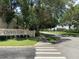 A tranquil street view showcasing the 'Osprey Cove' sign and lush green landscape, enhanced by mature trees at 2826 Osprey Cove Pl # 103, Kissimmee, FL 34746