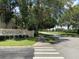 A tranquil street view showcasing the 'Osprey Cove' sign and lush green landscape, enhanced by mature trees at 2826 Osprey Cove Pl # 103, Kissimmee, FL 34746