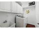 Well-lit laundry room featuring ample storage space with white cabinets and modern washer at 3618 Rothbury Dr, Belle Isle, FL 32812