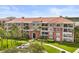 Multi-story building with red-tiled roof, manicured lawn, and mature trees offers a picturesque and inviting community setting at 5012 Shoreway Loop # 10107, Orlando, FL 32819