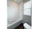 Bathroom with tiled tub and shower combination and window at 5107 Longmeadow Park St, Orlando, FL 32811