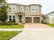 Two-story home featuring a two-car garage, brick driveway, and well-maintained landscaping at 5107 Longmeadow Park St, Orlando, FL 32811