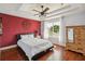 Spacious main bedroom featuring hardwood floors, a decorative ceiling fan, tray ceiling, and bright window at 5235 Keenes Pheasant Dr, Windermere, FL 34786