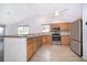 Bright kitchen featuring wood cabinets, stone countertops, stainless steel appliances, and tiled floors, open to the living space at 6512 Grosvenor Ln, Orlando, FL 32835