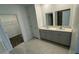 Bathroom featuring double sinks, gray vanity, and tiled floor with a walk in closet to the side at 680 Sand Pine Ln, Haines City, FL 33844