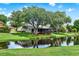 A beautifully landscaped backyard featuring a tranquil pond view and mature trees, with a cozy screened deck at 6836 Bittersweet Ln, Orlando, FL 32819