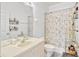 Bright bathroom featuring a single vanity, toilet, large mirror and tub-shower combination with floral curtains at 8152 Fan Palm Way, Kissimmee, FL 34747