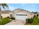 Beautiful single-story home with a two-car garage, manicured lawn and blooming bushes in front of the property at 8152 Fan Palm Way, Kissimmee, FL 34747