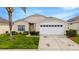 Charming single-story home with a two-car garage, manicured lawn and blooming bushes in front of the property at 8152 Fan Palm Way, Kissimmee, FL 34747