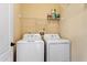 A laundry room with a side-by-side washer and dryer unit and shelving above provides ample space for laundry tasks at 1210 San Jacinto Cir, Sanford, FL 32771