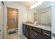 Bathroom vanity featuring granite countertops, double sinks, dark wood cabinets, and a glass-enclosed shower at 1292 Blue Island Dr, Clermont, FL 34714