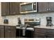 Close-up of the kitchen showcasing stainless steel appliances, granite countertops, and dark wood cabinets at 1292 Blue Island Dr, Clermont, FL 34714