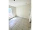 A bright bedroom featuring tiled floors, a window for natural light, and fresh paint at 1557 Venice Ln, Davenport, FL 33896