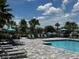 Community pool with lounge chairs, palm trees, and blue umbrellas at 1557 Venice Ln, Davenport, FL 33896