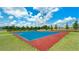 Outdoor basketball court in a community with a red and blue painted surface, surrounded by green grass at 15579 Water Spring Blvd, Winter Garden, FL 34787