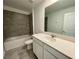 Bathroom with quartz vanity, large mirror, tiled shower/tub, and modern fixtures at 15579 Water Spring Blvd, Winter Garden, FL 34787