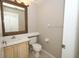 Cozy half bath with a decorative mirror above the single sink vanity at 2205 Wyndam Way, Kissimmee, FL 34743