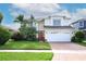 Charming two-story home with a well-manicured lawn, tropical plants, and a brick driveway at 2205 Wyndam Way, Kissimmee, FL 34743