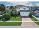 Charming two-story home with lush landscaping, brick driveway, and a vibrant red front door at 2205 Wyndam Way, Kissimmee, FL 34743