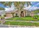 Charming brick home featuring a beautiful front yard with mature landscaping and a stately tree at 2265 Turnberry Dr, Oviedo, FL 32765