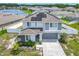 Aerial view of a modern home with solar panels, a two-car garage, and landscaped front yard near a pond at 242 White Heron Way, St Cloud, FL 34772