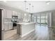 Modern kitchen featuring a large island, stainless steel appliances, and sliding glass doors leading to backyard at 242 White Heron Way, St Cloud, FL 34772