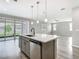 Stylish kitchen island with stainless steel dishwasher and sink, with a view of the backyard through glass doors at 242 White Heron Way, St Cloud, FL 34772