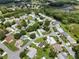 Aerial view of a well-maintained neighborhood with mature trees, landscaping, and pond at 25333 Casa Del Lago Ln, Leesburg, FL 34748