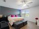 Bedroom with a gray accent wall, ceiling fan, two dark grey ottomans at the end of the bed, and natural light at 2918 Rodrick Cir, Orlando, FL 32824