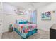 Vibrant bedroom showcases a colorful floral comforter, accented by turquoise pillows and whimsical art at 363 Miro Dr, Davenport, FL 33837