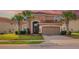 Beautiful two-story home showcasing a red-tiled roof, arched entryway, and lush palm trees at 381 Cabello Dr, Davenport, FL 33837