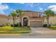 Charming two-story home showcasing a Spanish tile roof, arched entryway, and lush palm trees at 381 Cabello Dr, Davenport, FL 33837