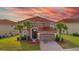 Two-story home featuring a red-tiled roof, arched entryway, palm trees, and well-kept lawn at 381 Cabello Dr, Davenport, FL 33837