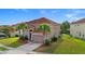 Two-story tan home with red tile roof, palm trees, and a well-maintained lawn at 381 Cabello Dr, Davenport, FL 33837