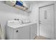 This laundry room includes a washer, dryer, storage shelving, and a door labeled 