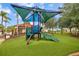Community playground with colorful structures, shade, slide, and green turf at 381 Cabello Dr, Davenport, FL 33837