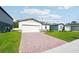Inviting one-story home with a brick driveway, attached garage, green lawn, and well-maintained landscaping at 4709 Jasmine Cir, Leesburg, FL 34748