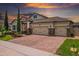 Charming home with a brick driveway, three-car garage, manicured lawn, and attractive landscaping under a colorful sunset sky at 5182 Appenine E Loop, St Cloud, FL 34771