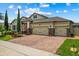 Charming home with a brick driveway, three-car garage, manicured lawn, and attractive landscaping under a bright blue sky at 5182 Appenine E Loop, St Cloud, FL 34771
