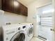 Laundry room featuring front-loading washer and dryer, upper cabinets, and garage access at 5431 Lochdale Dr, Orlando, FL 32818