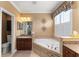 Ensuite bathroom featuring a soaker tub with granite accents, vanity, and plantation shutters for natural light at 600 Egret Place Dr, Winter Garden, FL 34787